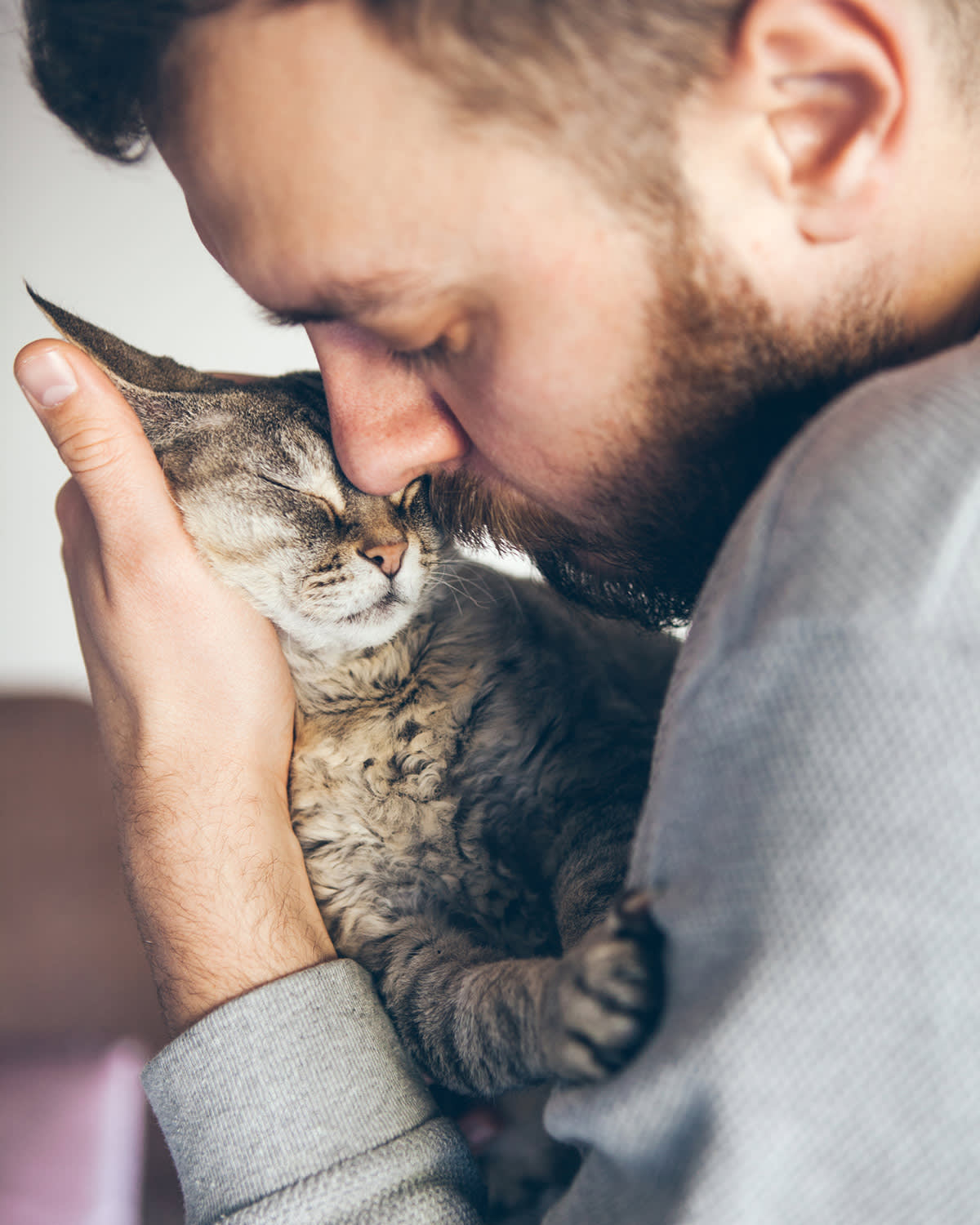 man cuddling cat with eyes closed