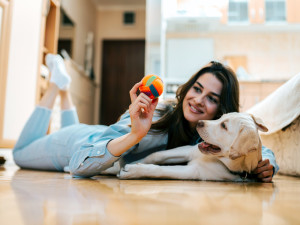 Woman and her dog playing with a ball.