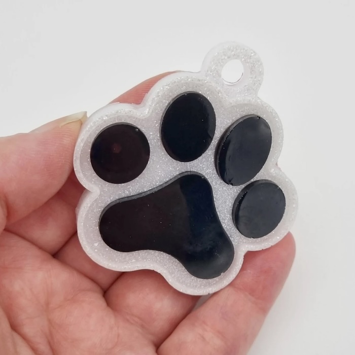a white and black keyring of a paw print