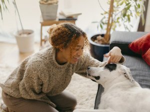 A woman smiling at a dog on a couch. 