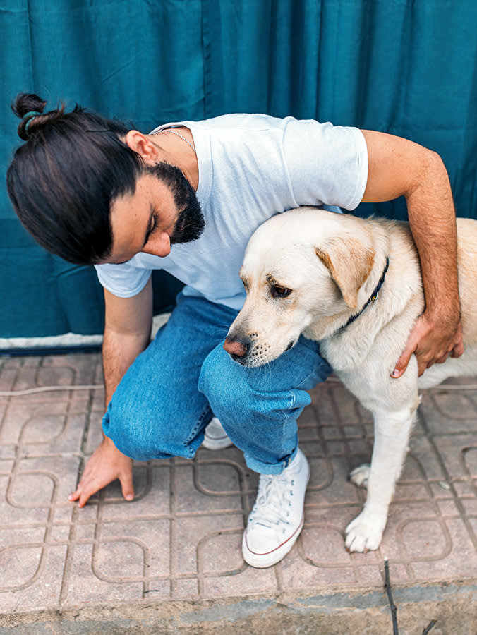 Man comforting his Labrador dog outside.
