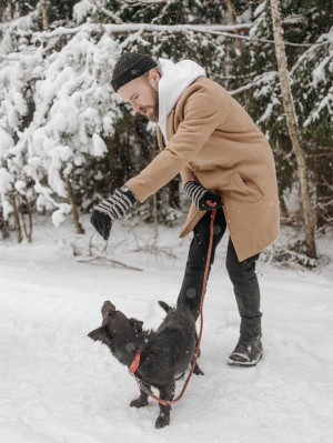 man untangling dog from leash in the snow