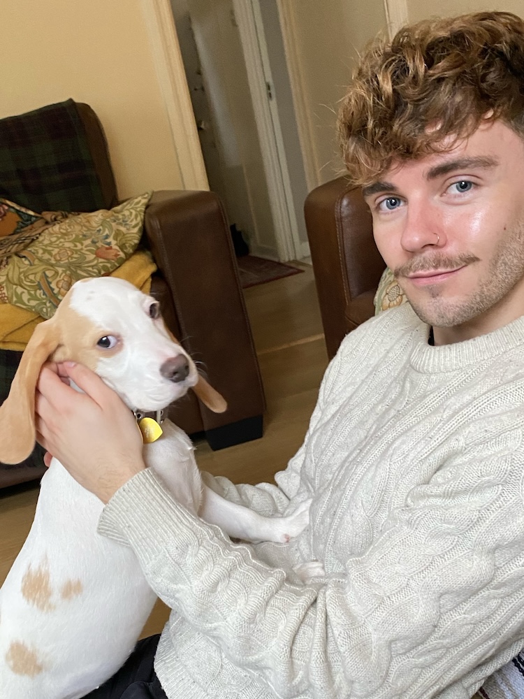 a picture of a man with a moustache cuddling a beagle puppy