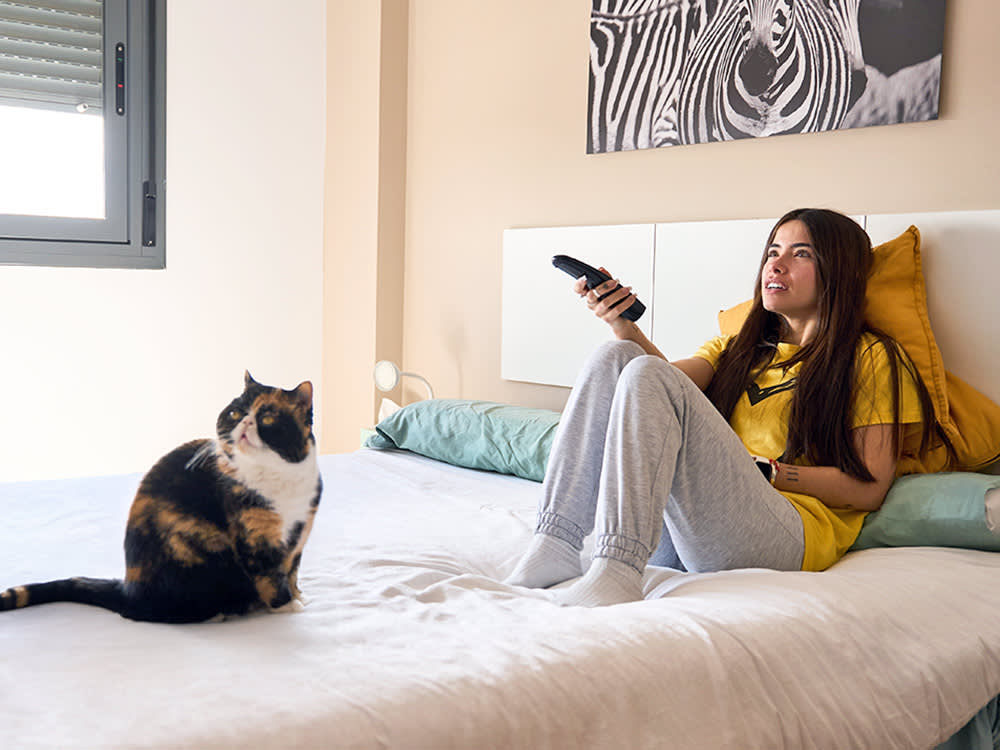 Woman watching tv with her cat at home.