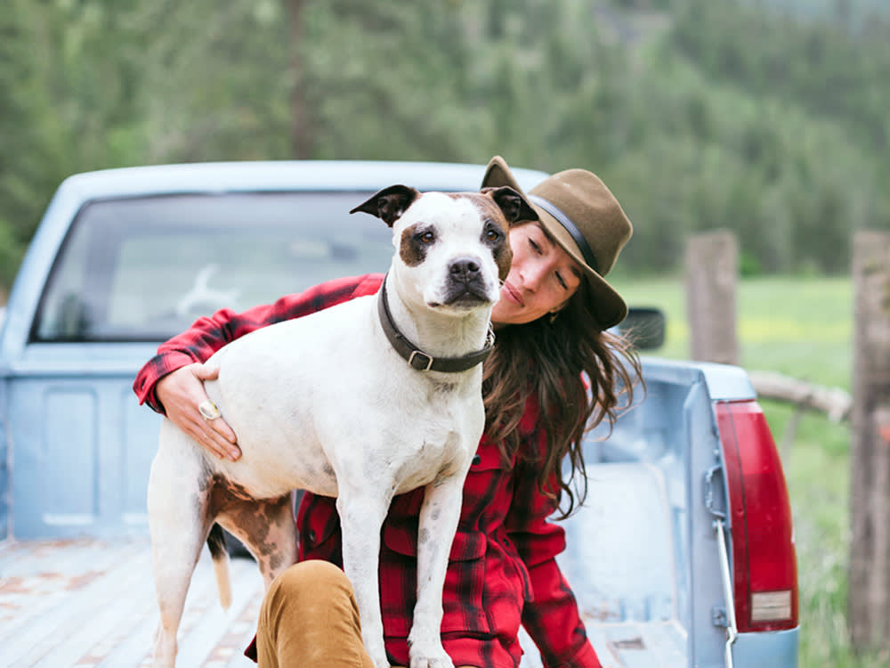 Woman hanging out with her dog in a truck outdoors.