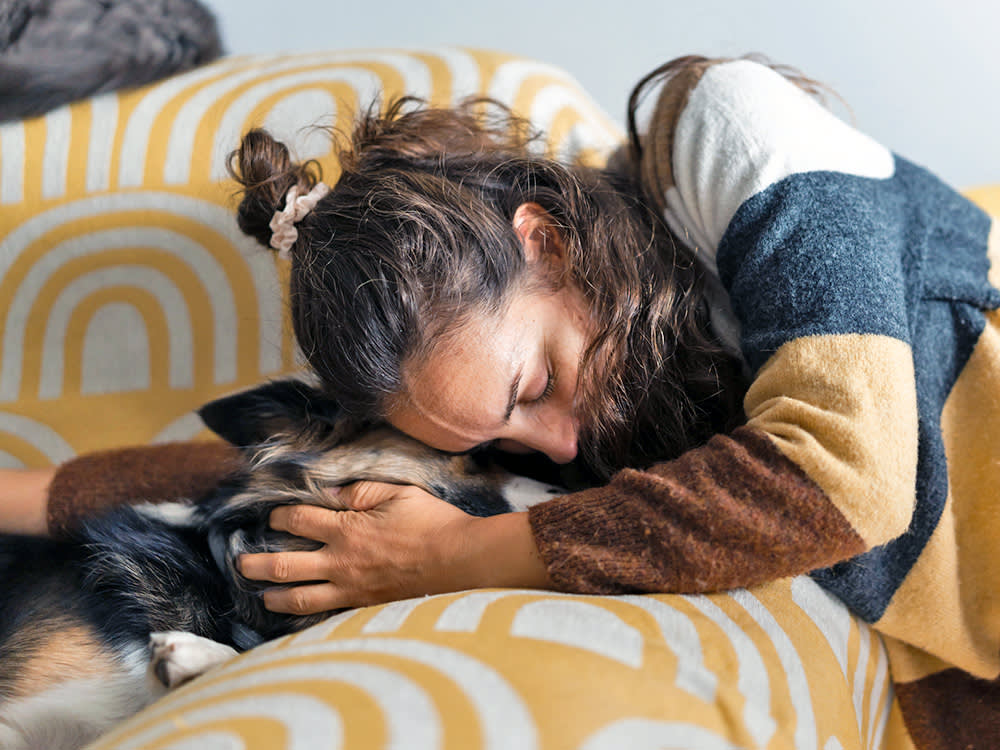 person hugging their dog on a sofa