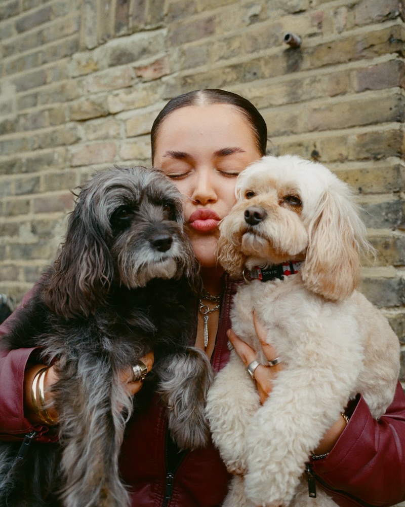 a woman holding two dogs puckers her lips in a kiss