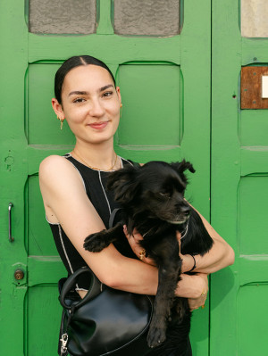 Happy young woman with her back dog in front of a green garage door in a street in Paris France.