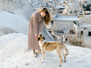woman on a beach in greece petting a stray dog