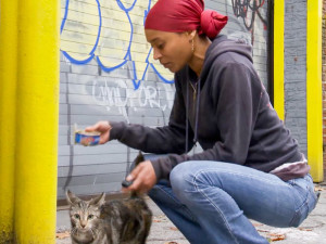 Latonya “Sassee” Walker feeding a cat on the sidewalk