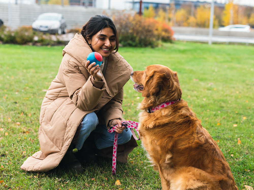 Happy woman playing outside in the grass with dog.

