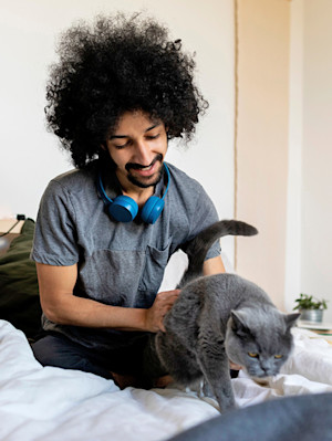Man petting his gray cat at home.