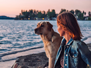 Woman sitting on the beach with a dog.