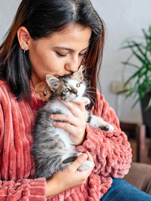 Woman cuddling kitten at home.