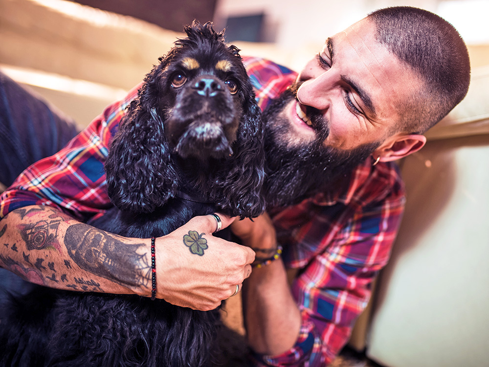Man hugging his cute black dog at home.