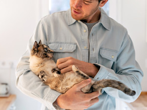 Man holding his cat in his arms at home.