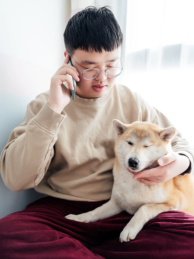Man with glasses on the phone with dog on his lap