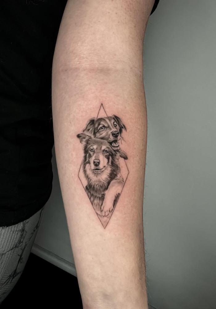 A hyper-realistic black and white tattoo of two dogs. 