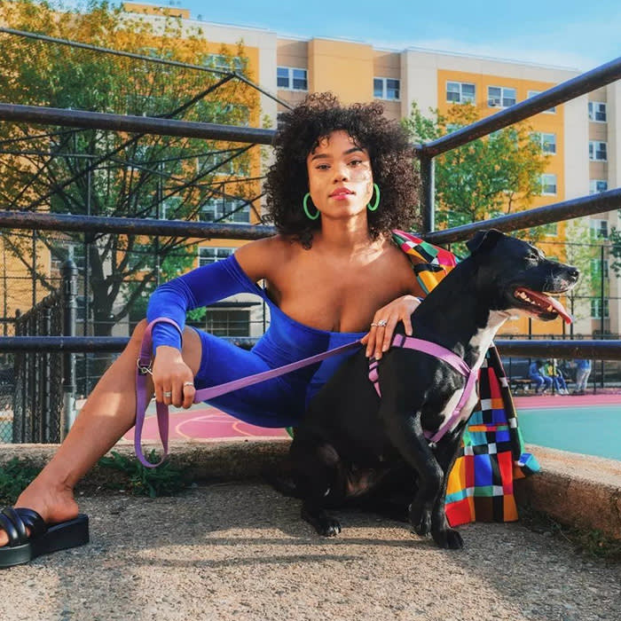 model crouching next to black dog on lavender leash