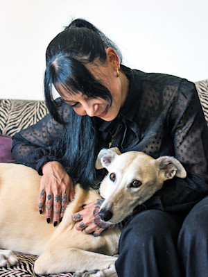 Woman cuddling her dog at home on the couch.