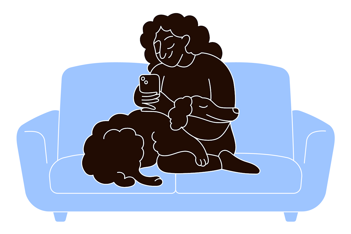 a pet parent snuggling their dog on the couch while scrolling through their phone