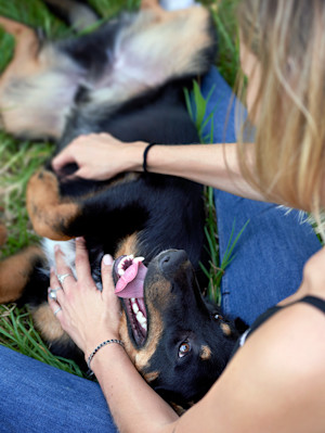 Woman petting her dog outside in the grass.