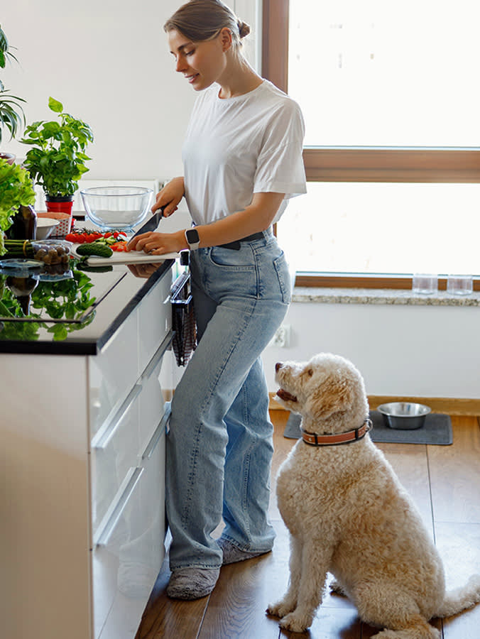 Woman cooking in her kitchen with dog waiting.