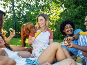 Woman and friends enjoying a picnic with their dog outside.