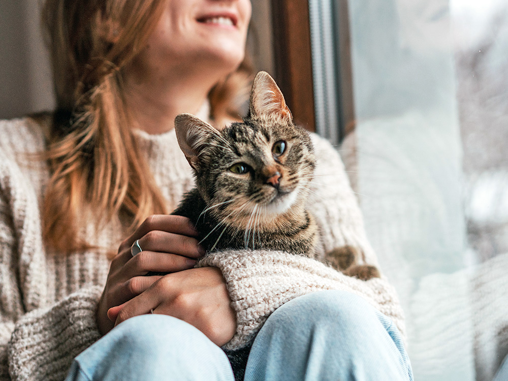 Woman at home with cat in her lap.