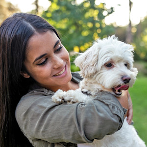 College woman holding her small white fluffy dog.