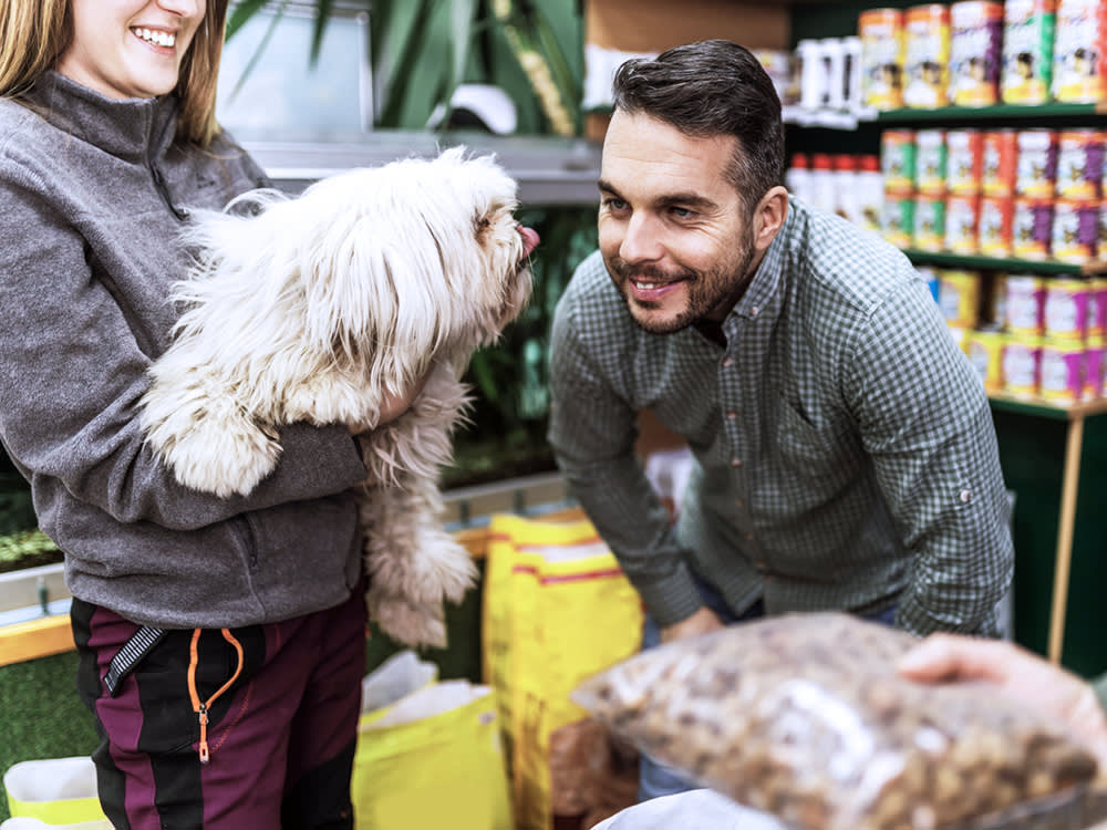 a man smiles at a fluffy white dog in a pet food store