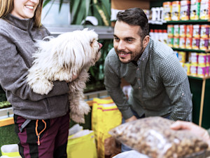 a man smiles at a fluffy white dog in a pet food store