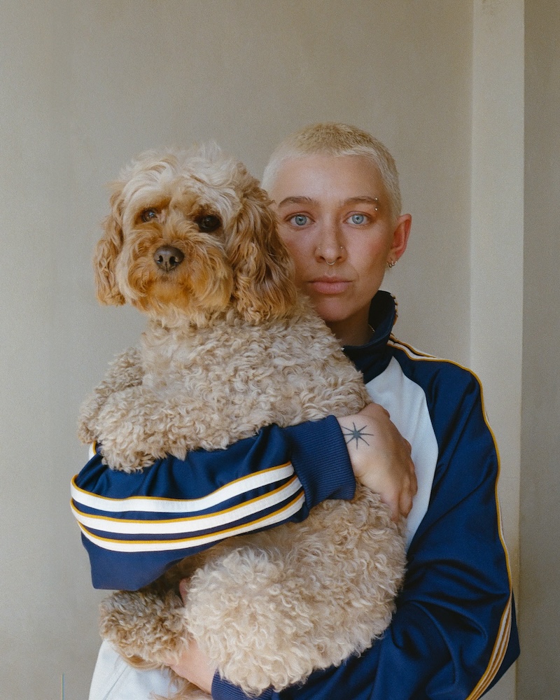 Picture of a woman with cropped bleached hair holding a golden dog