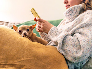 Woman snuggling at home with her small dog.