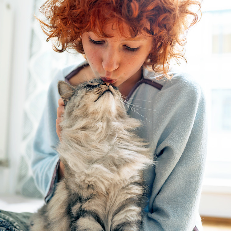 Woman snuggling cat at home.