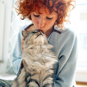 Woman snuggling cat at home.
