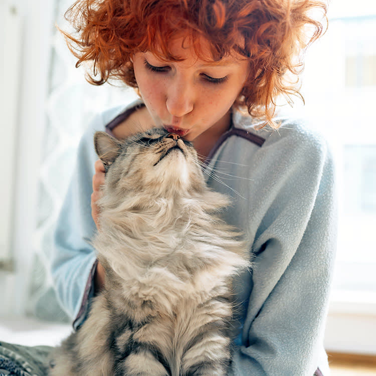 Woman snuggling cat at home.