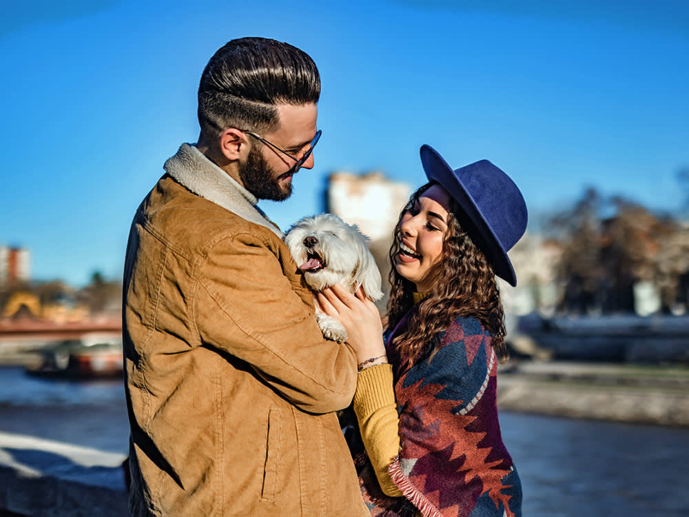 Couple smiling and holding their small fluffy dog.