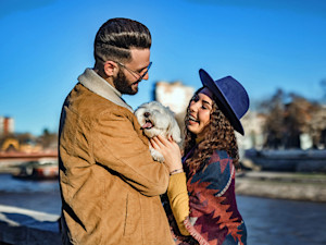Couple smiling and holding their small fluffy dog.