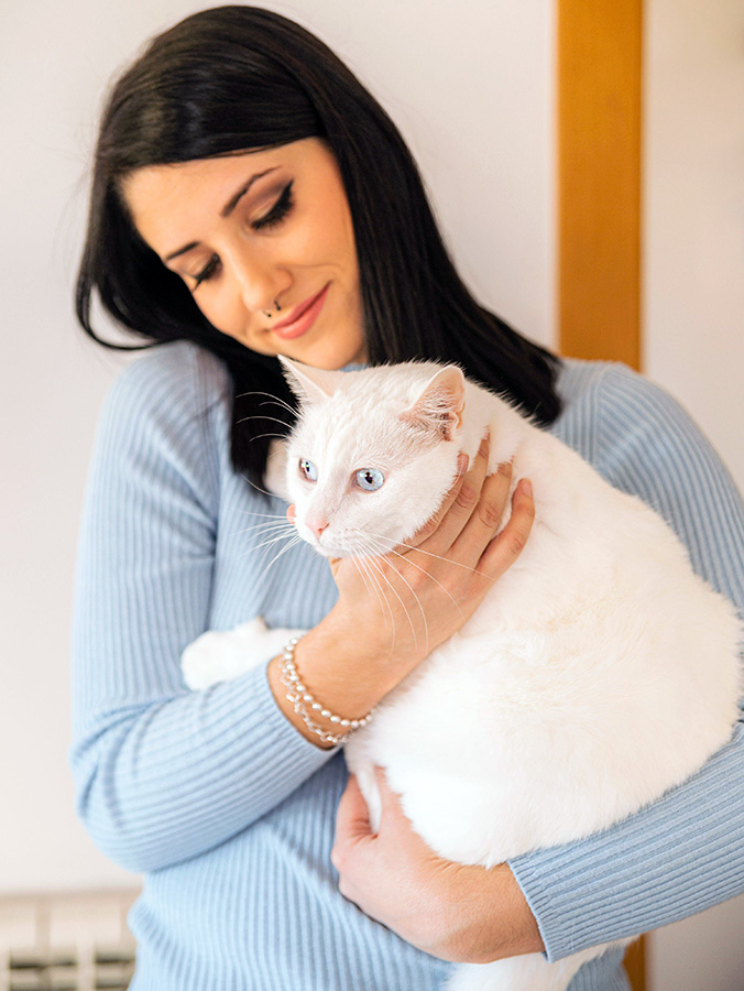 Woman holding her pregnant cat in her arms.
