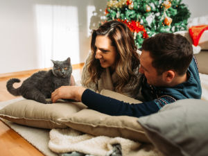 Couple laying on the floor with their kitten during Christmas