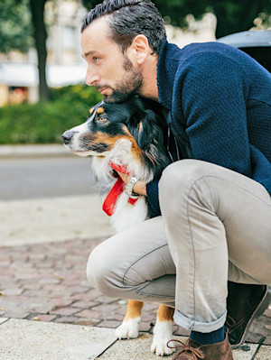 Man hugging his dog outside in the city.
