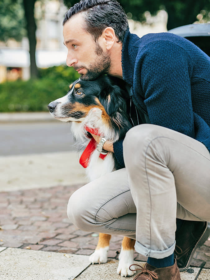 Man hugging his dog outside in the city.