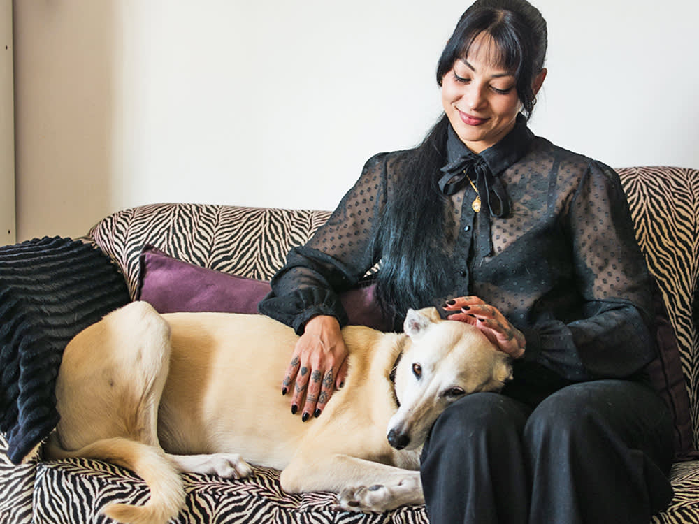 Woman petting her dog on the couch.