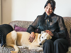 Woman petting her dog on the couch.