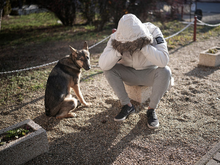 a man kneels beside his dog 