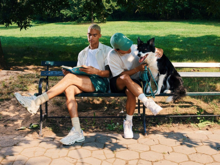 two people sit on a bench with their large black and white dog