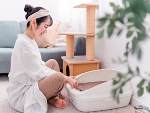 Woman cleaning cat's litter box.