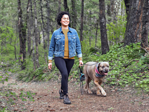 Woman walking her dog in the woods.