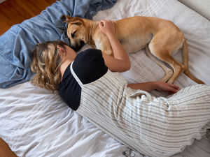 puppy snuggling in bed with person